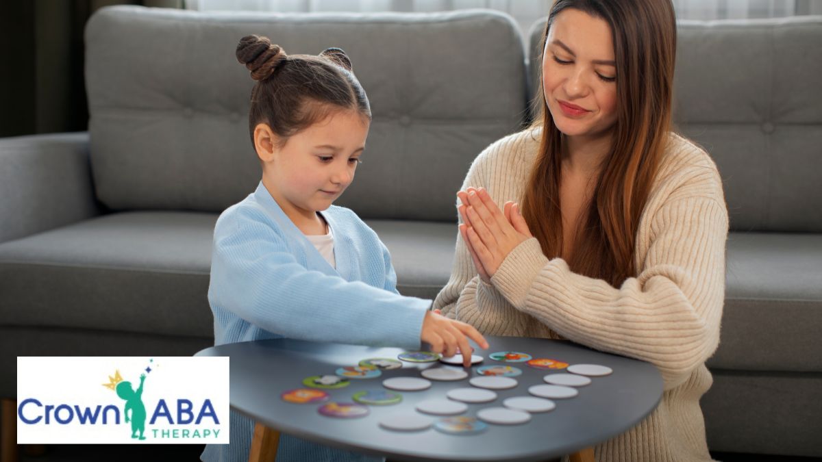 A therapist supports a young child during in-home play therapy to build social skills in the living room.