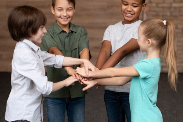 Kids join hands at center of circle practicing social skills through ABA activity.