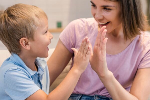 A parent celebrates progress with child through high five during ABA therapy at home.