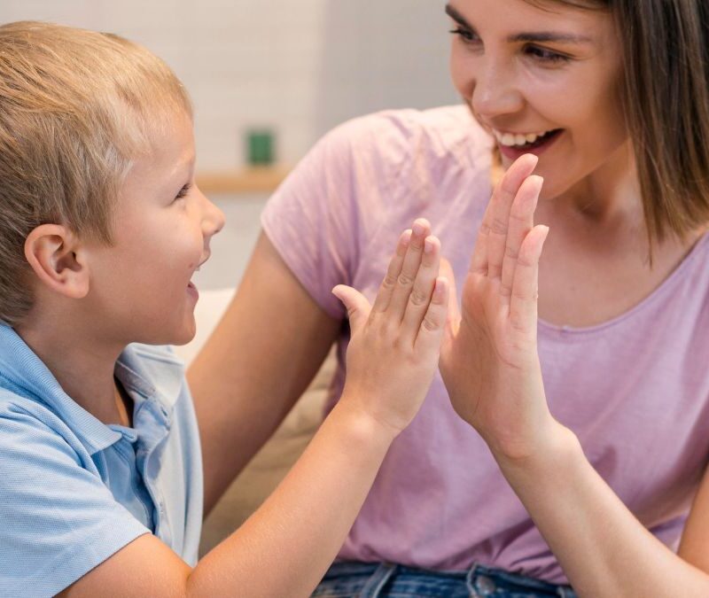 A parent celebrates progress with child through high five during ABA therapy at home.