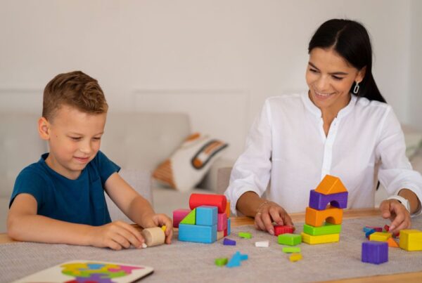 ABA therapist guiding a young boy through play-based activities to build social skills.