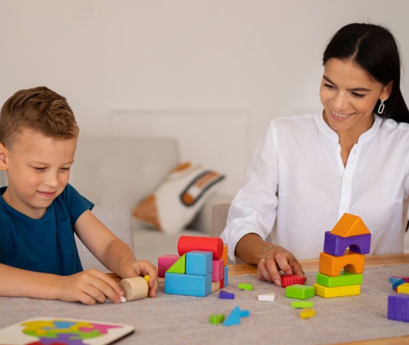 ABA therapist guiding a young boy through play-based activities to build social skills.